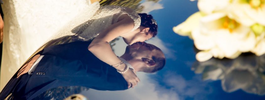 Brautpaar spiegelt sich im Kofferraum des HochzeitsAutos