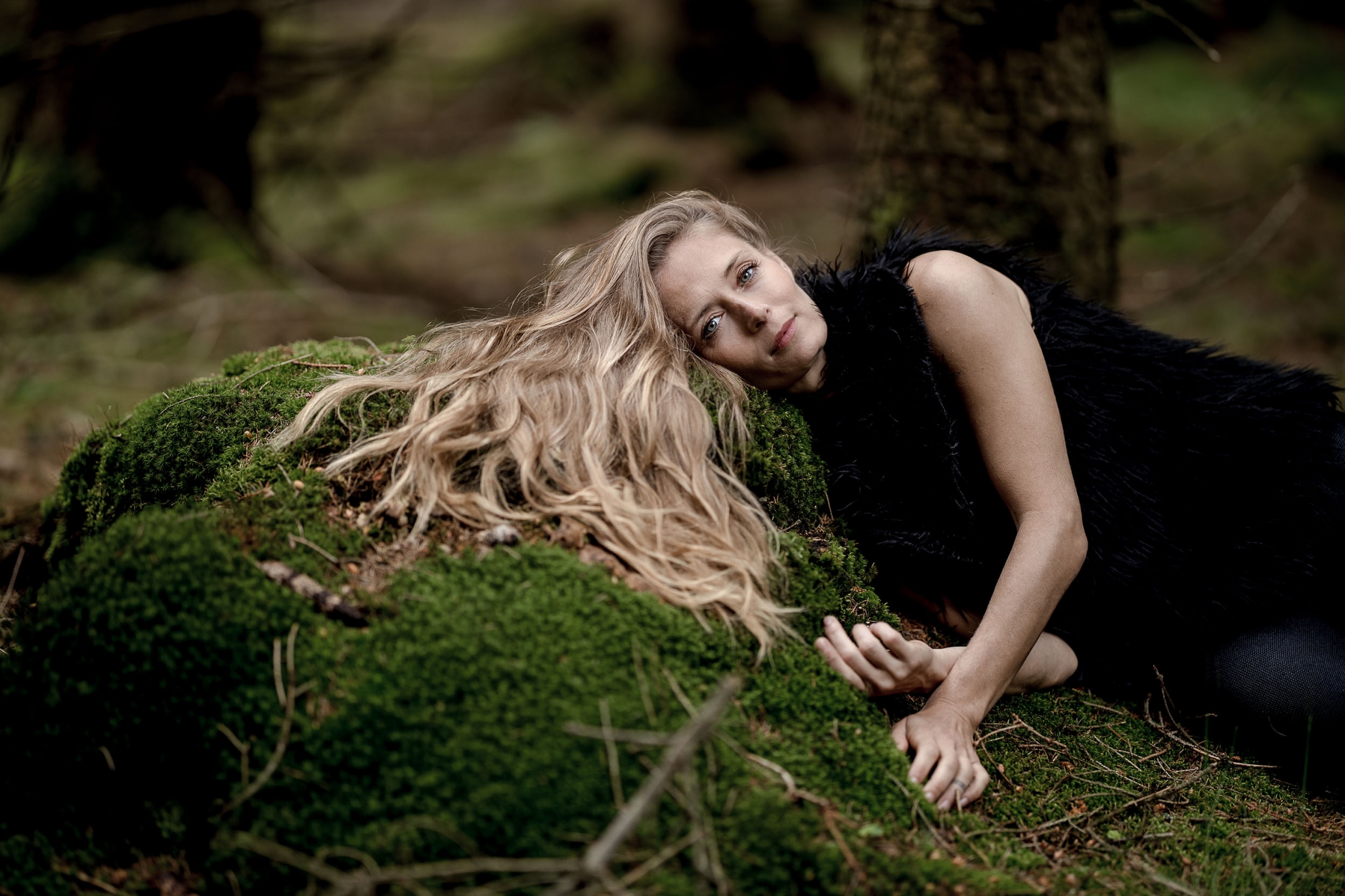 Frau mit langen blonden Haaren liegt seitlich im grünen Moos fotografiert am Bhf Rennsteig im Thüringer Wald mit der Canon EOSR & RF 85mm f/1.2L USM