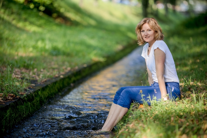 natürliches Ganzkörperportrait der Yogalehrerin Monika Freeman Ganzkörperaufnahme der Yogalehrerin Monika Freeman, Füße im Wasser baumelnd, frische Sommerfarben Canon EOSR6 & EF 135mm f2.0L USM