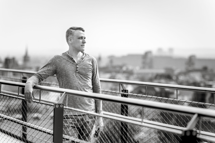 ein junger Mann schaut von einer Brücke über der Stadt von links nach rechts in die Weite fotografiert in Erfurt mit der Canon EOS R6m2 & dem RF 85mm f1.2