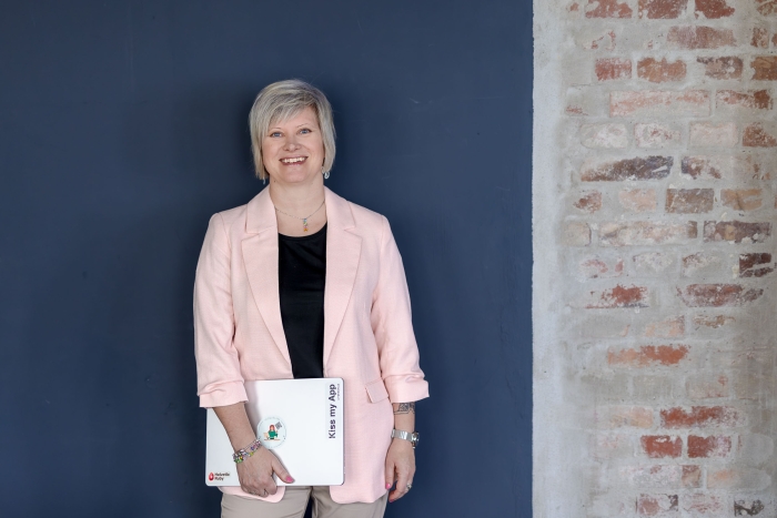 Selbstbewusste Unternehmerin mit Laptop Porträt einer Geschäftsfrau mit Laptop in der Hand, die selbstbewusst vor einer interessanten Wandkulisse steht. Die Wand ist teils dunkelblau gestrichen, teils unverputzter Backstein.