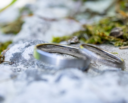 Zwei Ringe, die das Versprechen ewiger Liebe symbolisieren, ruhen auf moosbedecktem Stein fotografiert in Kranichfeld bei Erfurt mit der Canon EOS R5M2 & dem RF 35mm f1.8