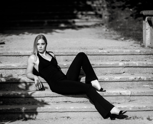 Das zeitlose Styling der Frau erinnert an die Ästhetik von Chanel, schlichte und zeitlose Eleganz in klassischen schwarz weiss, fotografiert im harten Sonnenlicht in Bad Langensalza mit der Canon EOS R5 MK2 & dem RF 135mm f1.8