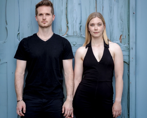 Ein neuer Weg - Paarbild Ein Bild, das den Kontrast zwischen der modernen schwarzen Kleidung des Paares und dem verwitterten, blauen Holz der Tür hervorhebt, fotografiert in Bad Langensalza mit der EOS R5M2 & dem RF 85mm f1.2