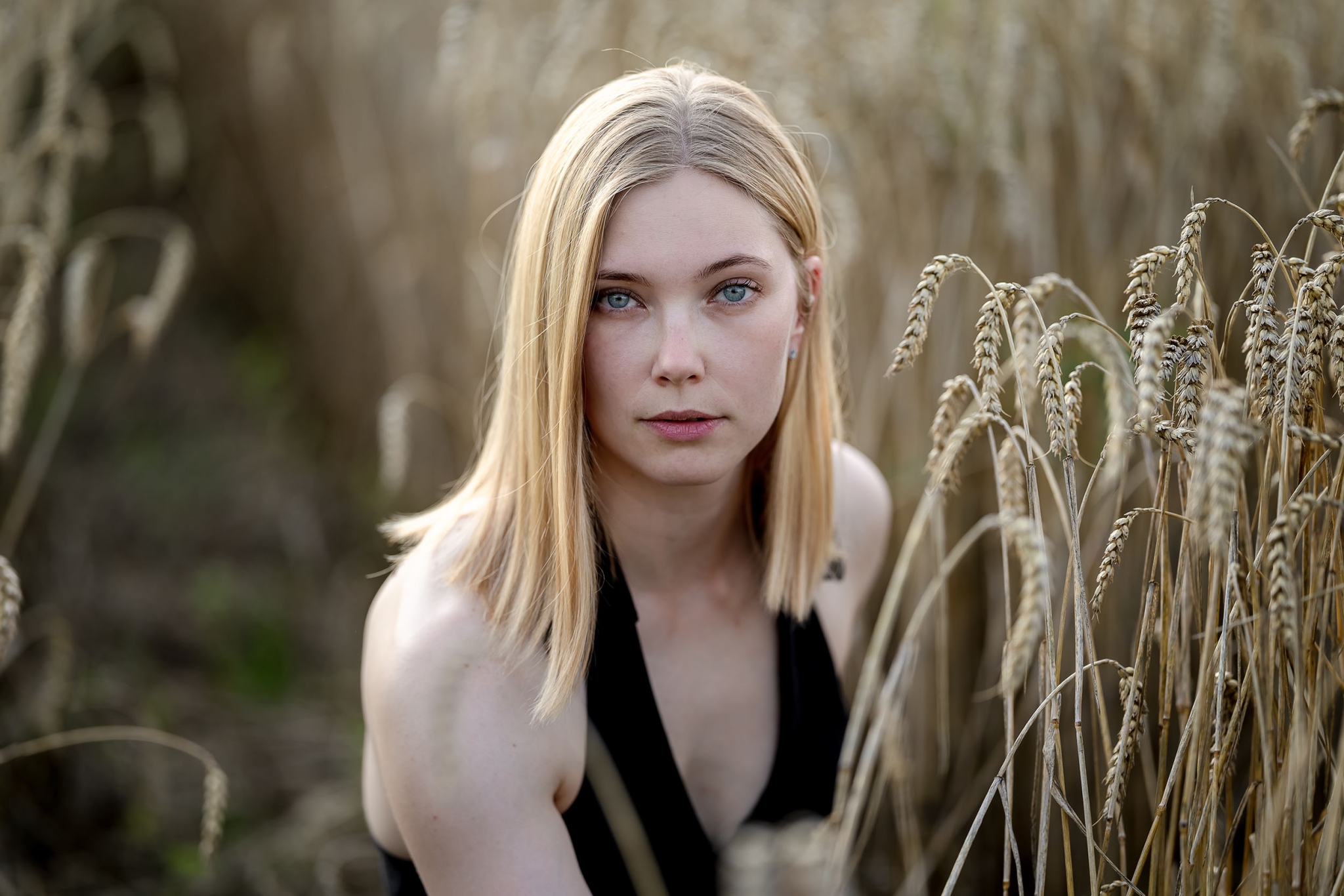 Umgeben von reifem Getreide strahlt eine Frau in diesem natürlichen Porträt eine ruhige und unmittelbare Präsenz aus, mit Tagelicht fotografiert in Bad Langensalza mit der Canon EOs R5II & dem RF 135mm