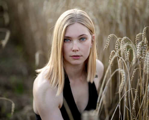 Umgeben von reifem Getreide strahlt eine Frau in diesem natürlichen Porträt eine ruhige und unmittelbare Präsenz aus, mit Tagelicht fotografiert in Bad Langensalza mit der Canon EOs R5II & dem RF 135mm