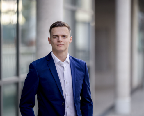 Corporate Porträt junger Mann in Erfurt Modernes Corporate Headshot eines jungen Geschäftsmanns vor einer hellen Glasfassade mit weichem Bokeh im Hintergrund.