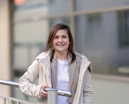 Business Casual Look Modernes Umfeld Businessporträt einer Frau im Layering-Outfit aus Shirt, Karoblazer und Jacke vor moderner Architektur. Equipment: Canon EOS R5M² & RF 85mm f1.2.
