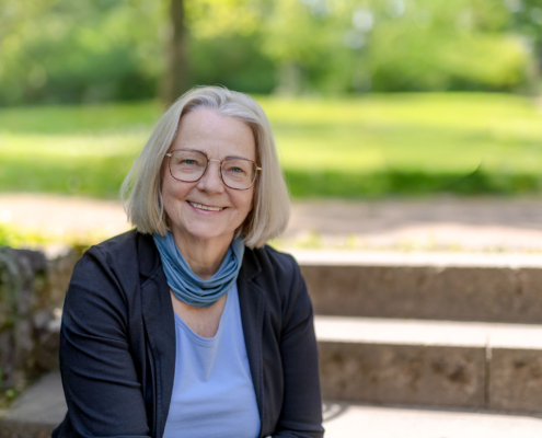 Authentische Peoplefotografie Thüringen Porträt einer sympathischen Frau im Businesslook mit Brille in einer Parkanlage.