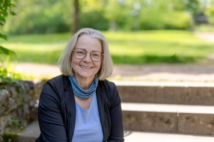 Authentische Peoplefotografie Thüringen Porträt einer sympathischen Frau im Businesslook mit Brille in einer Parkanlage.