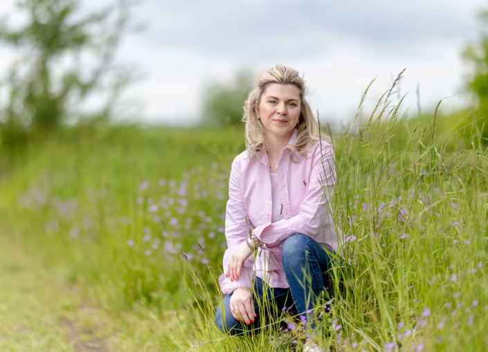 authentische & natürliche Porträtfotografie Professionelles Porträt einer Frau in einer sommerlichen Wiese sitzend